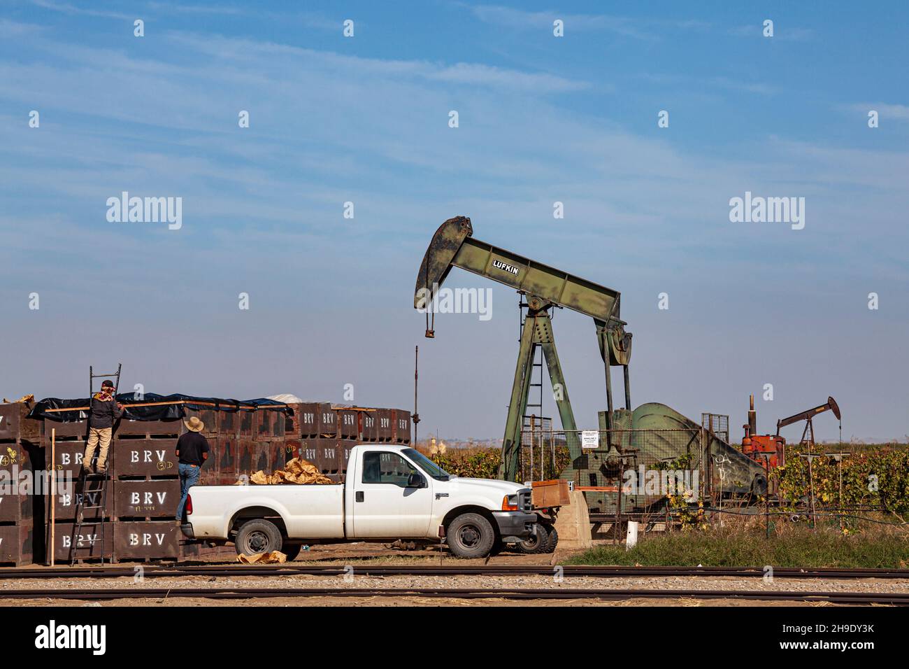 Agricultural workers next to oil well in the Mountain View Oil Field