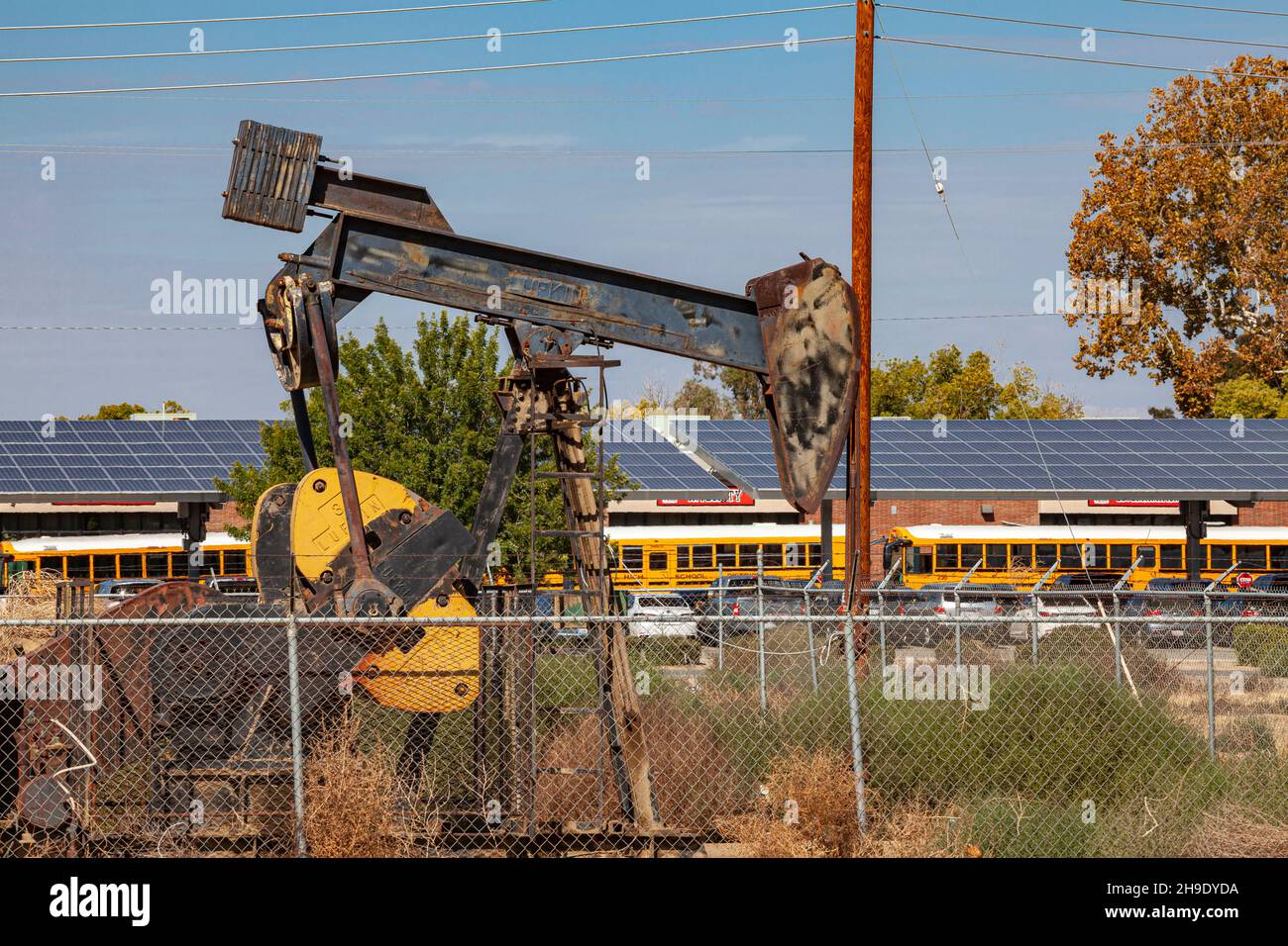 Pumpjack near school buses, Arvin, Kern County, California, USA Stock