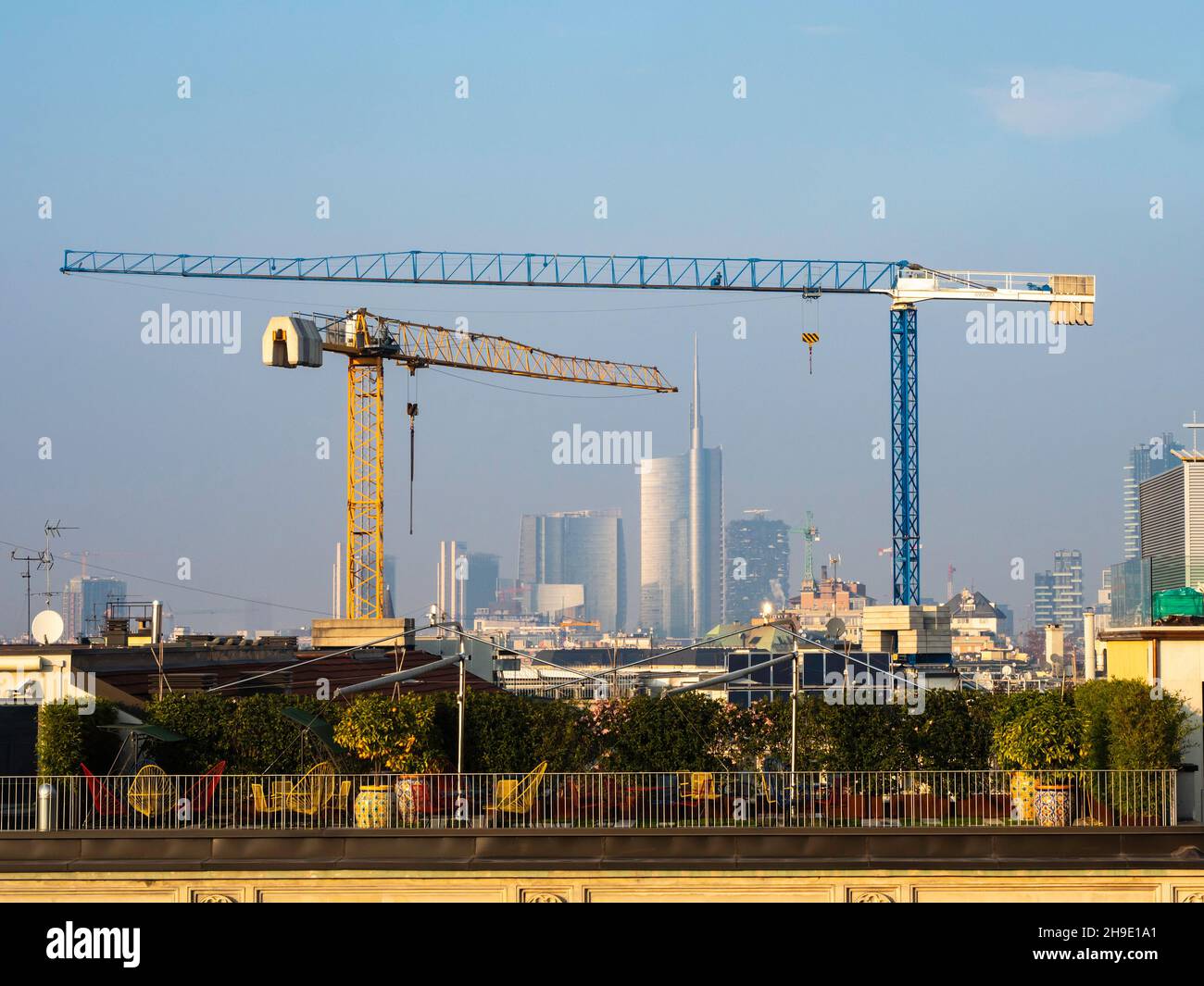Two construction cranes with the city of Milan in the background Stock Photo