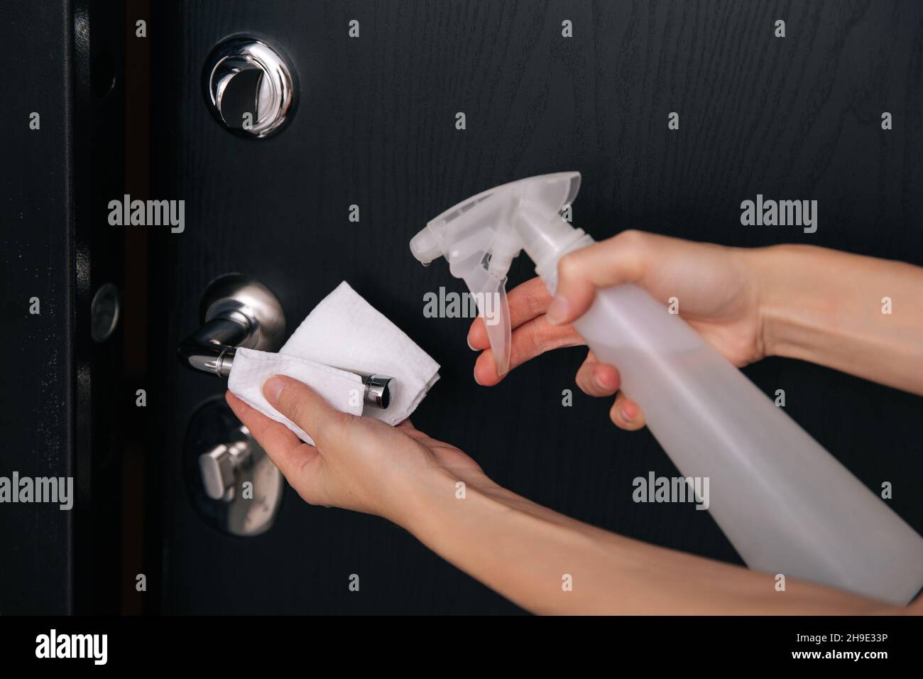 Cleaning black door handles with an antiseptic wet wipe. Woman hand