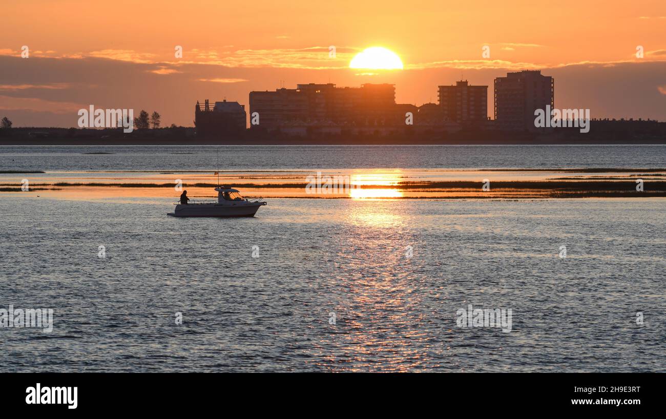 Sunrise in the Santoña marshes with Laredo in the background and a boat in the marsh Stock Photo