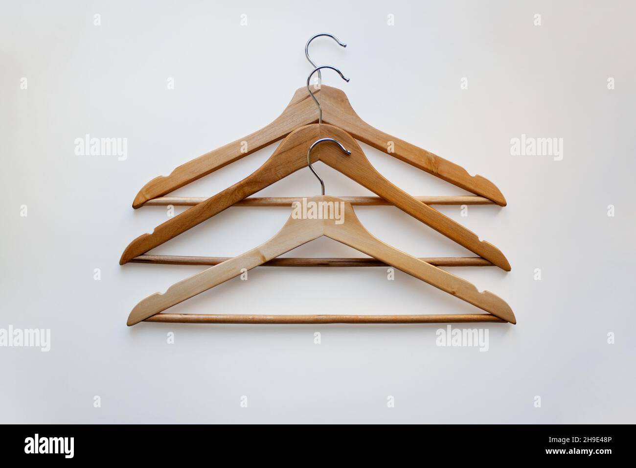 https://c8.alamy.com/comp/2H9E48P/three-wooden-coat-hangers-isolated-on-white-background-from-a-high-angle-view-2H9E48P.jpg