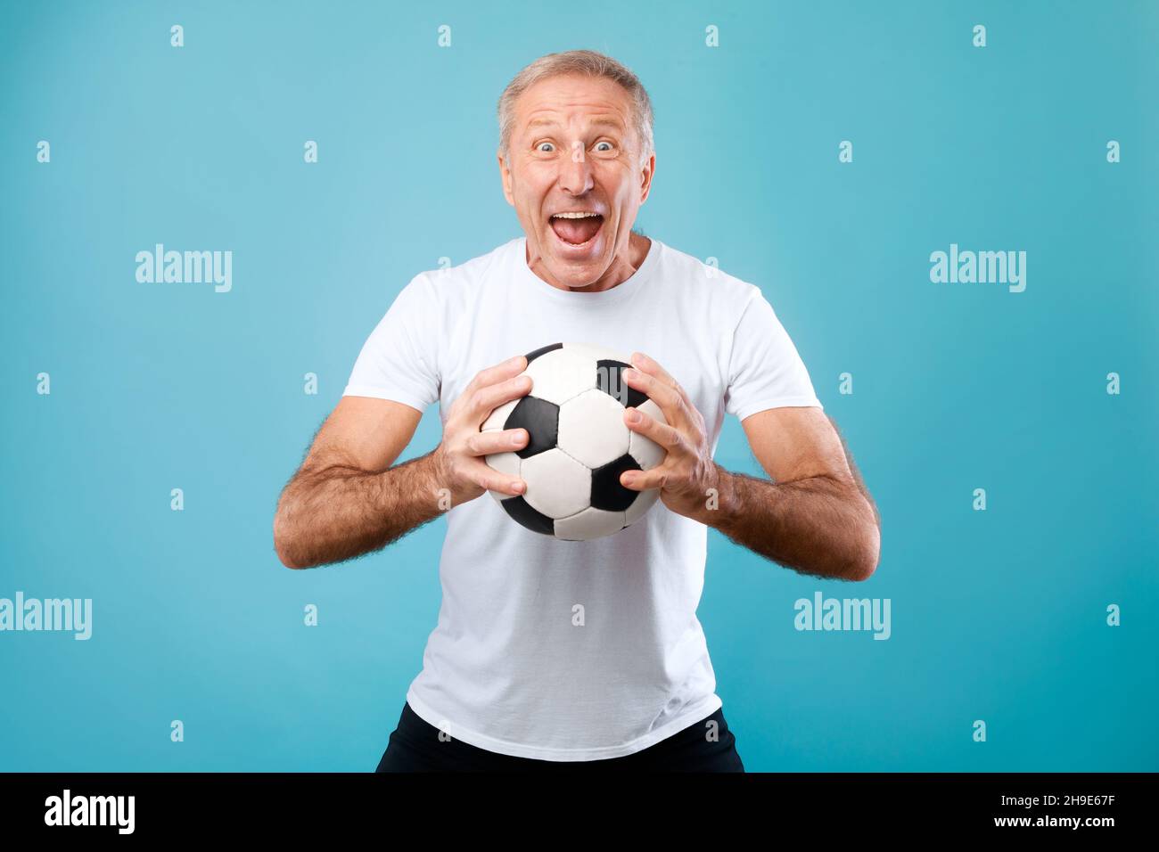 Mature man posing with soccer ball on blue background Stock Photo - Alamy