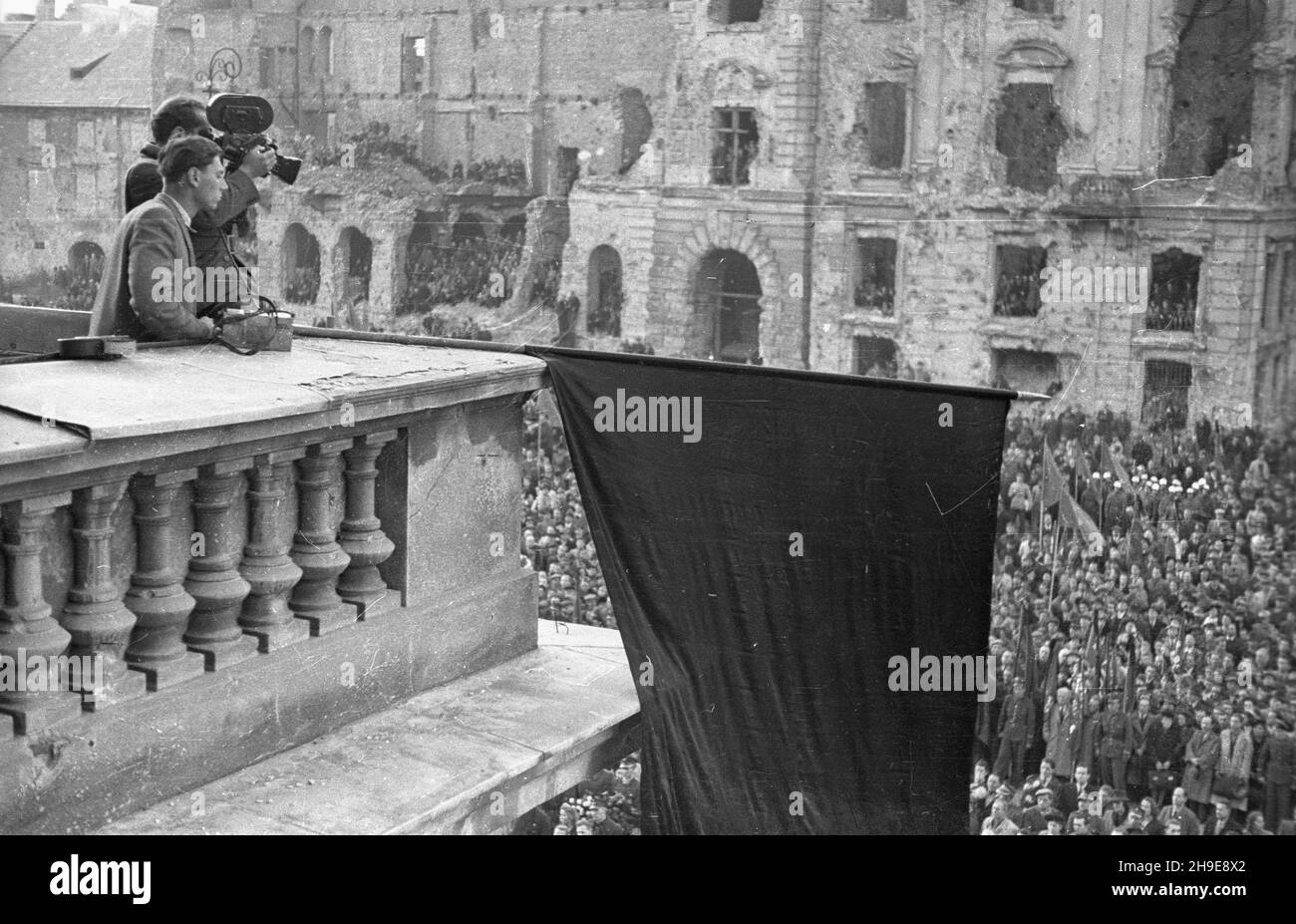 Warszawa, 1947-10-16. Stutysiêczna manifestacja na placu Teatralnym dla uczczenia pamiêci 50 ¿o³nierzy Gwardii Ludowej powieszonych przez Niemców w 1942 r. w odwecie za wysadzenie torów kolejowych. By³a to pierwsza publiczna egzekucja w okupowanej Warszawie. Nz. ekipa Polskiej Kroniki Filmowej (za kamer¹ W³adys³aw Forbert, obok Mieczys³aw Wiesio³ek) z tarasu Teatru Wielkiego filmuje t³um ze sztandarami i transparentami. W tle zrujnowany pa³ac Jab³onowskich. wb/gr PAP Warsaw, Oct. 16, 1947. A 100,000-strong demonstration in honour of 50 People's Guard soldiers hanged by Germans in 1942 in Stock Photo