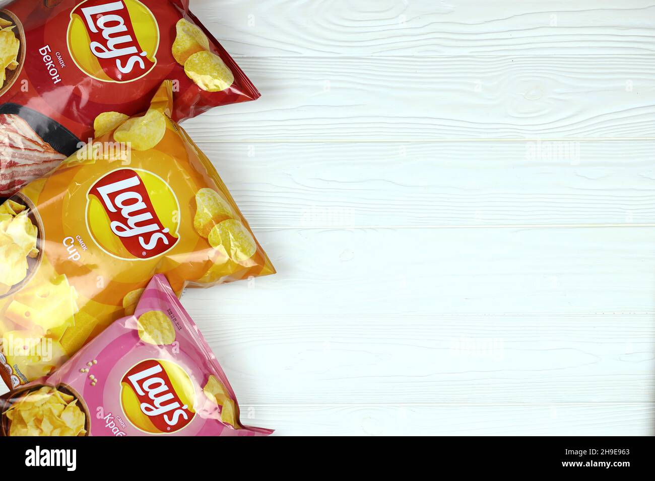 KHARKOV, UKRAINE - JANUARY 3, 2021: Various flavoured of lay's potato chips on wooden background. Lay's has been owned by PepsiCo through Frito-Lay si Stock Photo