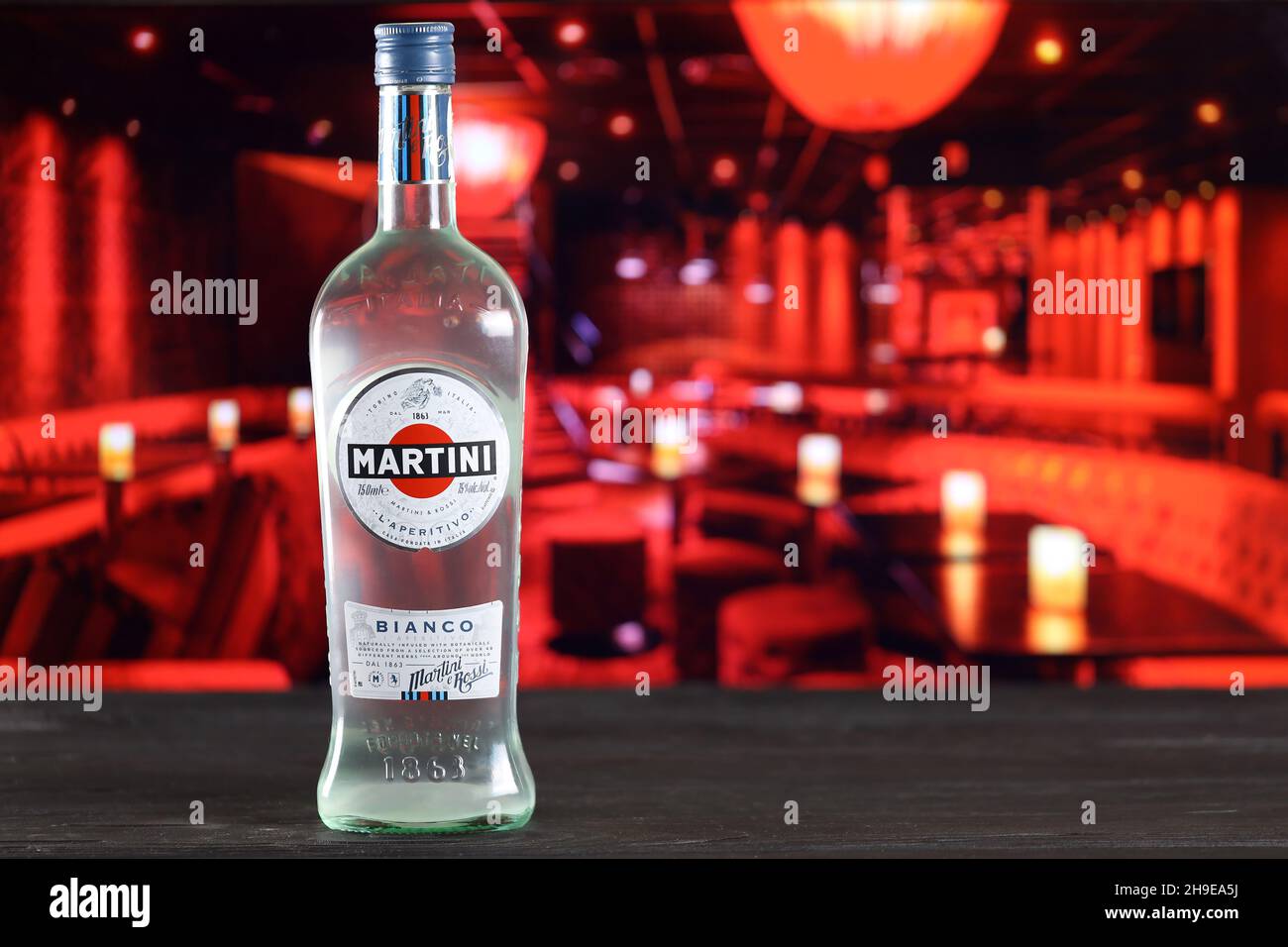 KHARKOV, UKRAINE - FEBRUARY 14, 2021: Martini e Rossi blanco bottle on wooden table with red bar interior on background. Elite alcohol production Stock Photo