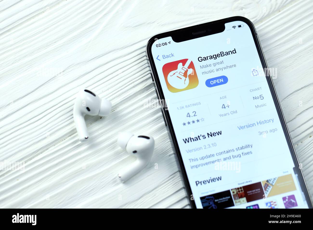 KHARKOV, UKRAINE - MARCH 5, 2021: Garageband for artists icon and application from App store on iPhone 12 pro display screen with airpods pro on white Stock Photo