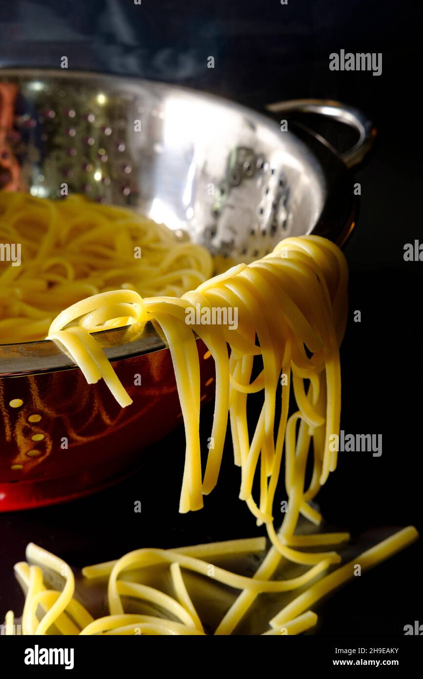 Straining linguine in red colander for Italian alfredo dinner Stock