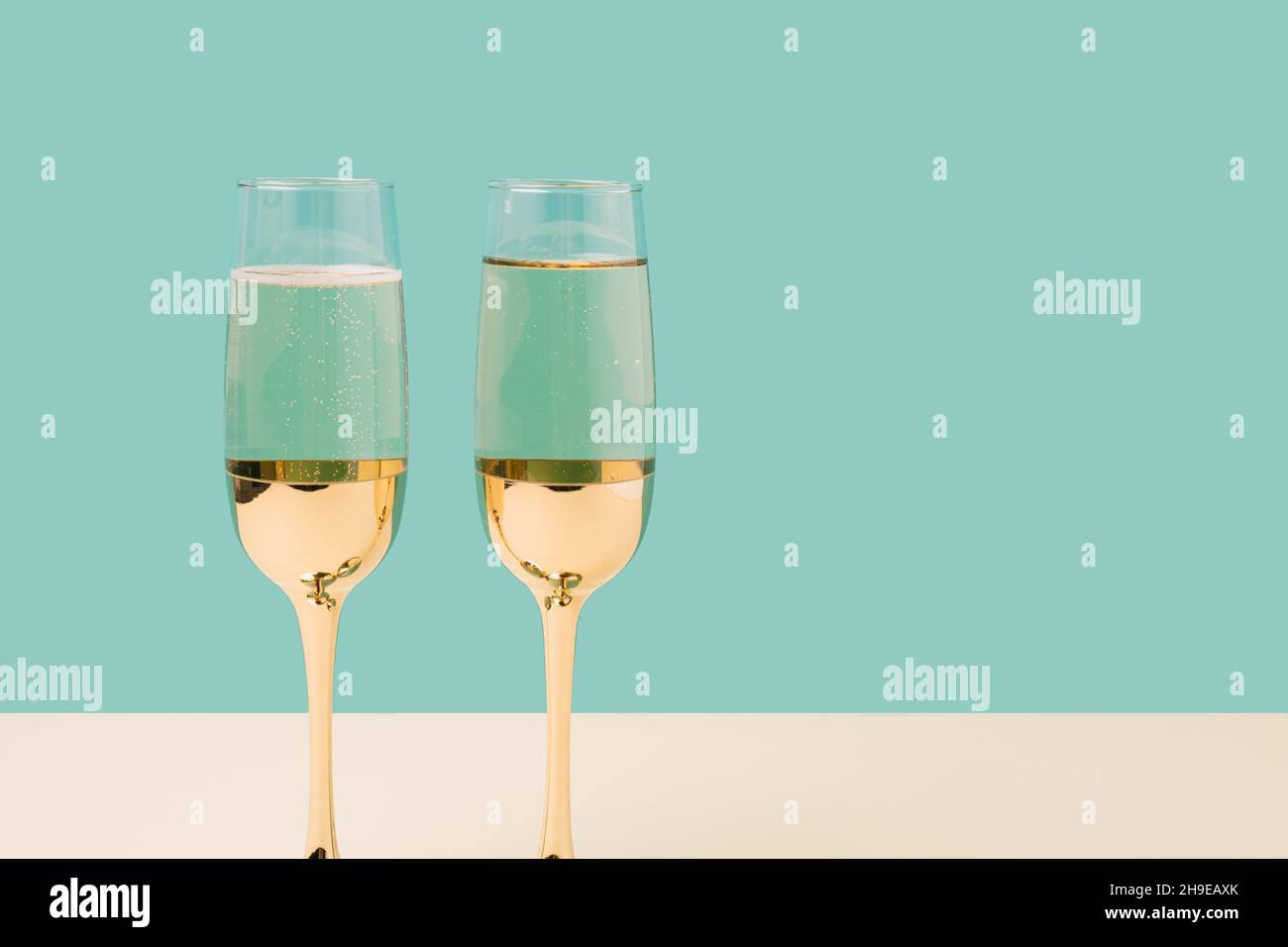 Romantic champagne glasses set up on a turquoise background. Minimal Valentines concept Stock Photo