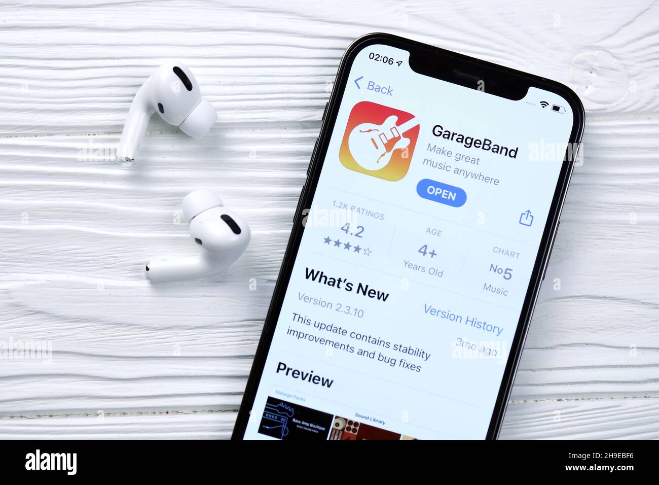 KHARKOV, UKRAINE - MARCH 5, 2021: Garageband for artists icon and application from App store on iPhone 12 pro display screen with airpods pro on white Stock Photo