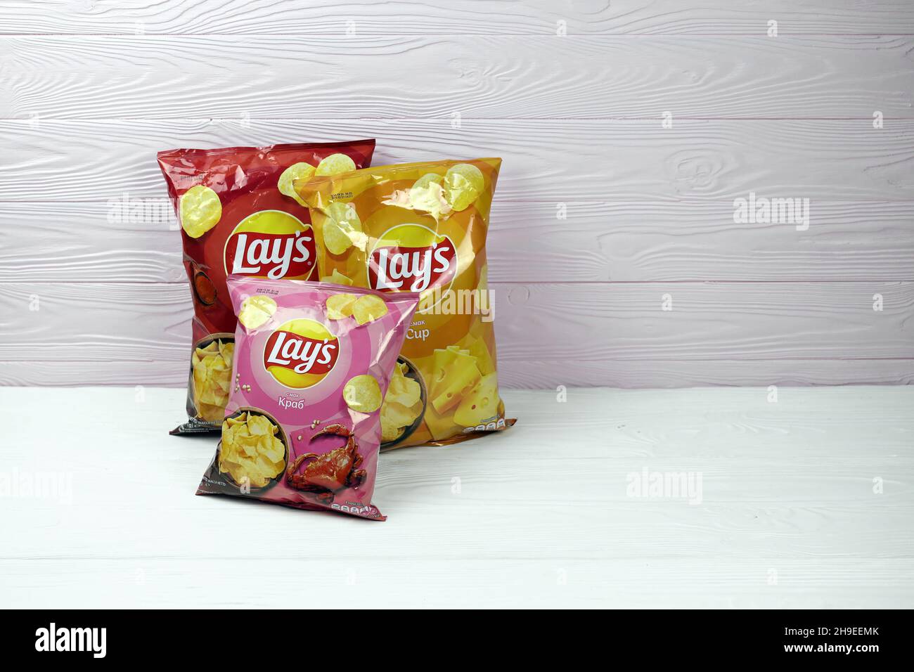 KHARKOV, UKRAINE - JANUARY 3, 2021: Various flavoured of lay's potato chips on wooden background. Lay's has been owned by PepsiCo through Frito-Lay si Stock Photo