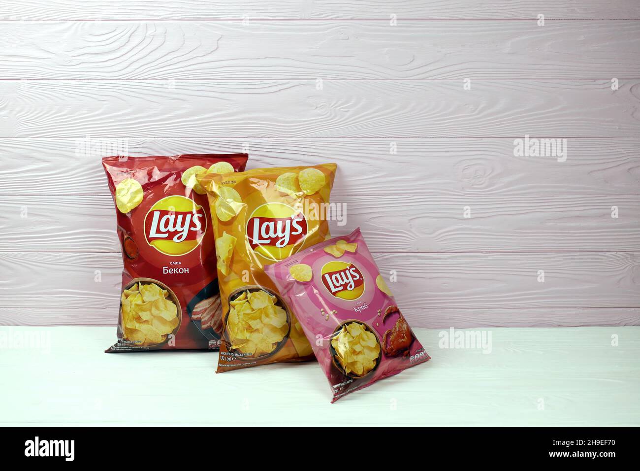 KHARKOV, UKRAINE - JANUARY 3, 2021: Various flavoured of lay's potato chips on wooden background. Lay's has been owned by PepsiCo through Frito-Lay si Stock Photo