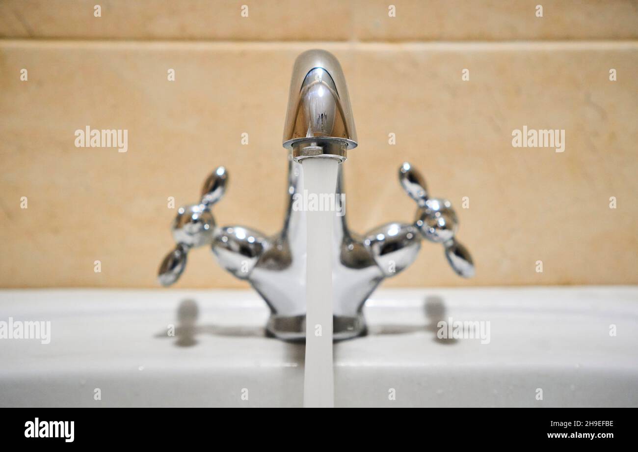 Common mixer tap. Water flowing out of bathroom stainless steel pillar