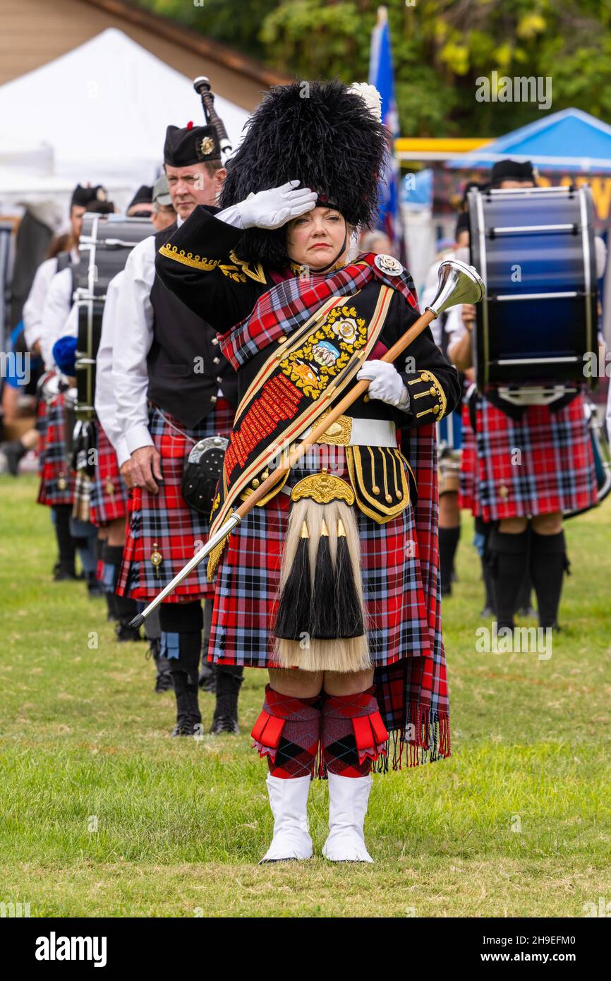 A HIghland drum major in her full regalia and mace renders a salute at