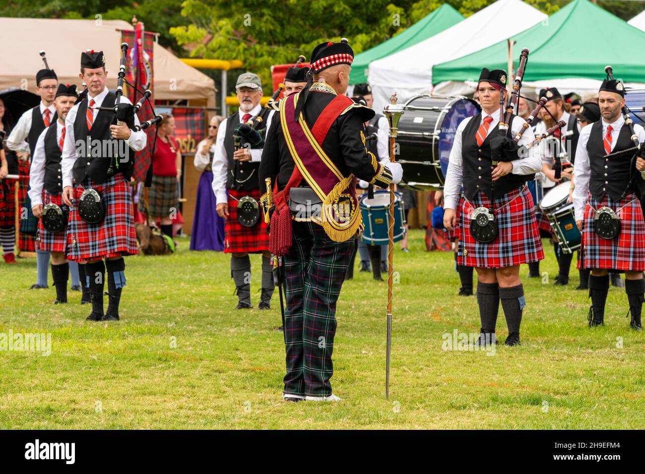 A Highland drum major in full regalia with his mace leads a pipe band