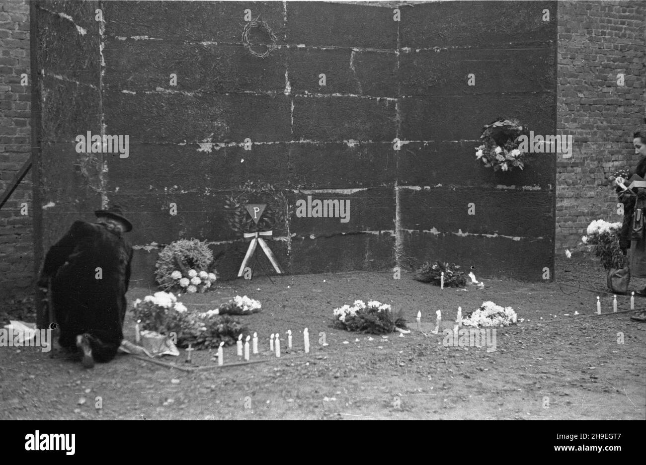 Oœwiêcim, 1947-11-01. By³y niemiecki obóz koncentracyjny Auschwitz-Birkenau. Nz. kwiaty i œwieczki przed œcian¹ œmierci na dziedziñcu bloku XI, gdzie dokonywano egzekucji. ps/gr  PAP      Oswiecim, Nov. 1, 1947. Former concentration camp Auschwitz-Birkenau. Pictured: flowers and candles at the death wall, the execution site, on the yard of the 11th block.  ps/gr  PAP Stock Photo