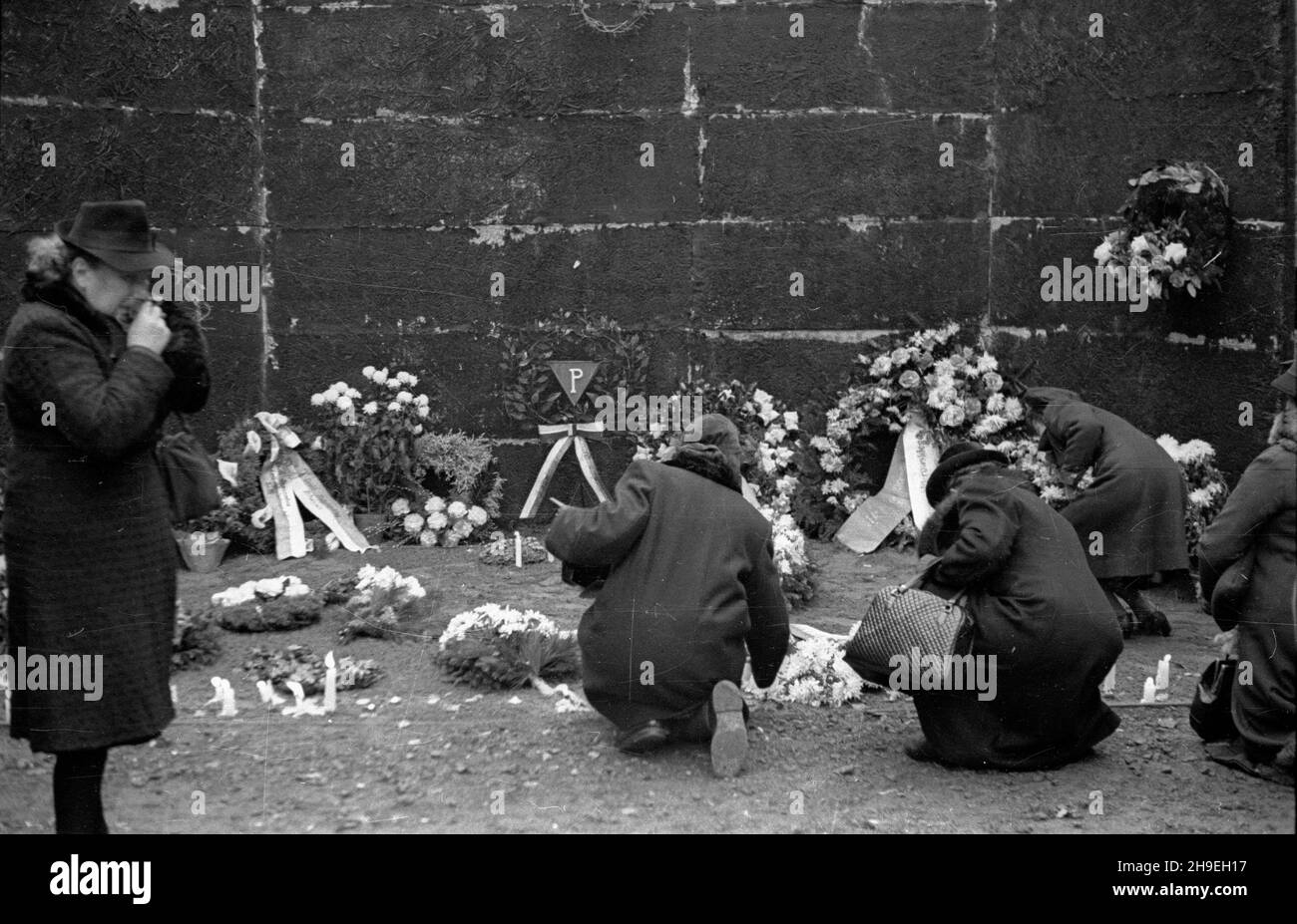 Oœwiêcim, 1947-11-01. By³y niemiecki obóz koncentracyjny Auschwitz-Birkenau. Nz. kobiety zapalaj¹ œwieczki przy œcianie œmierci na dziedziñcu bloku XI, gdzie dokonywano egzekucji. ps/gr  PAP      Oswiecim, Nov. 1, 1947. Former concentration camp Auschwitz-Birkenau. Pictured: girls lighting candles at the death wall, the execution site, on the yard of the 11th block.  ps/gr  PAP Stock Photo