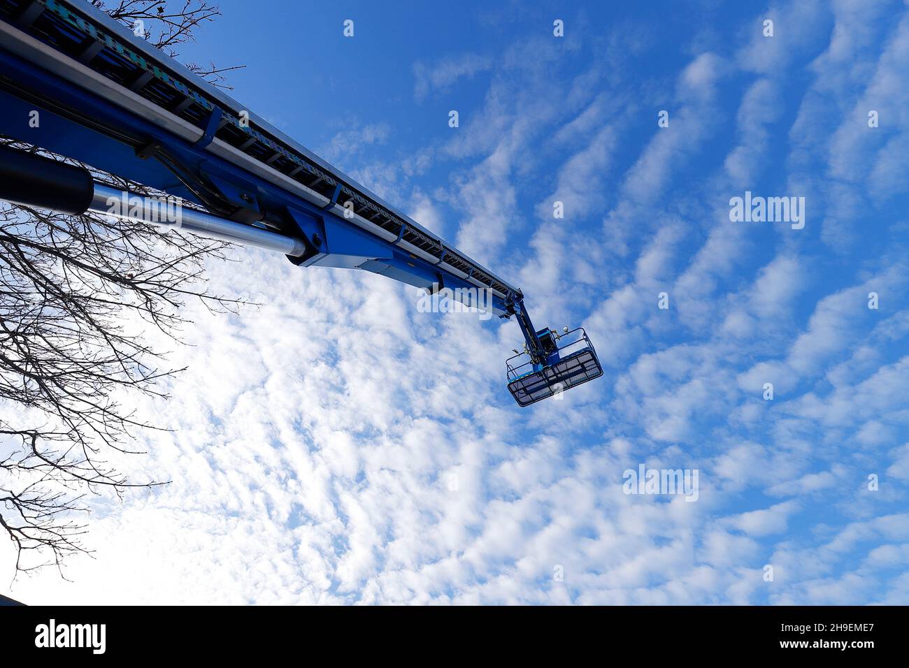 A Genie S125 boom lift against a cloudy blue sky Stock Photo