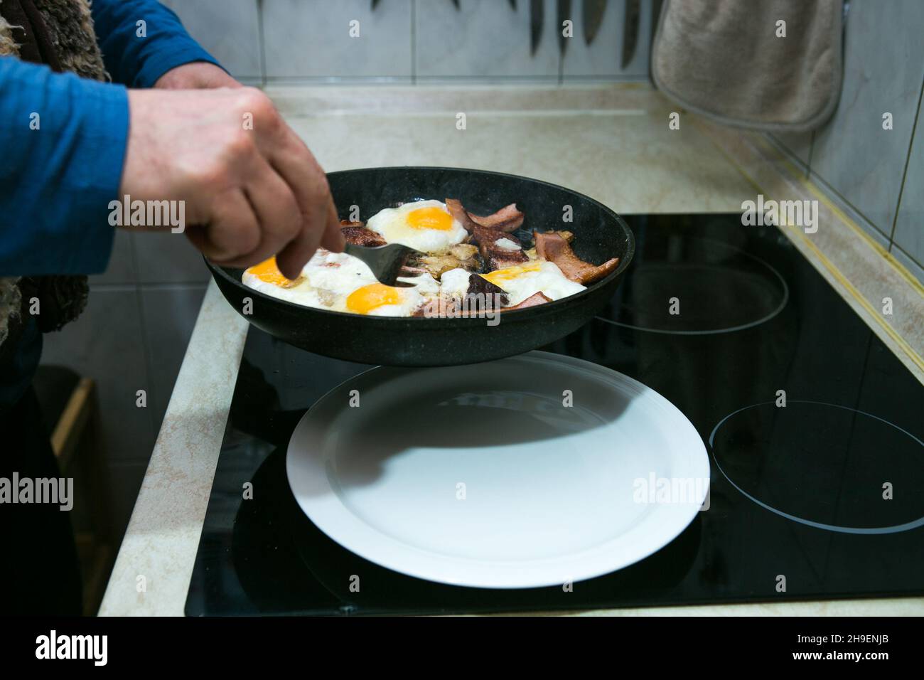 The process of cooking scrambled eggs with lard and sausage. The man