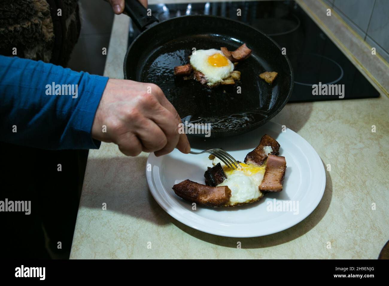 The process of cooking scrambled eggs with lard and sausage. The man
