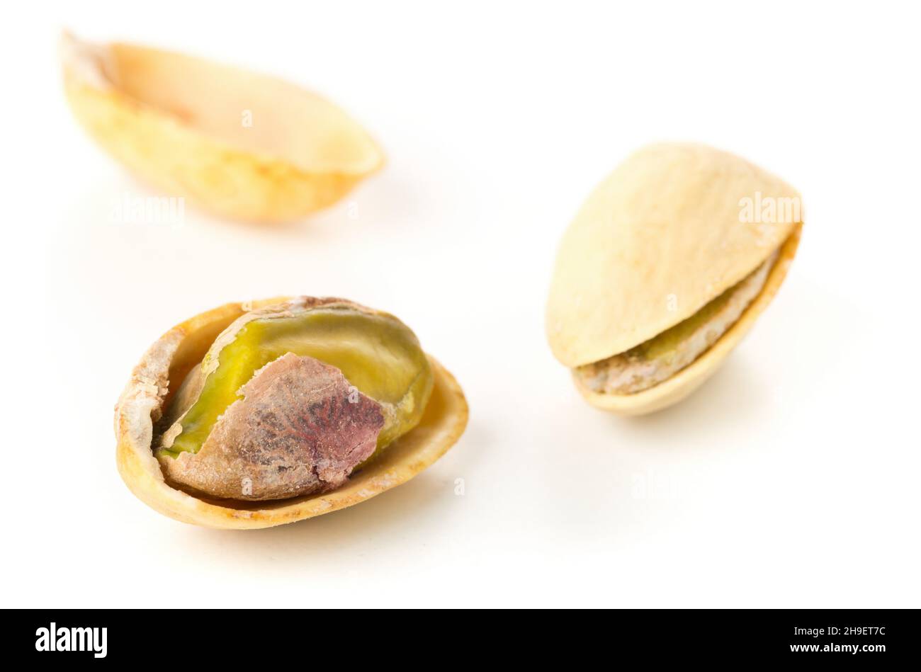 Macro of single salted, roasted green pistachio nut over white background, healthy food snack, selective focus Stock Photo