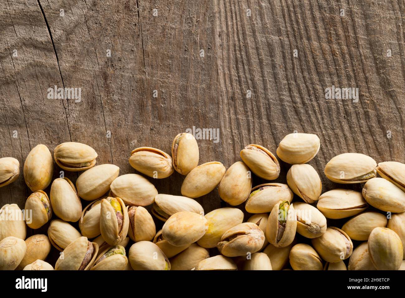 Border of salted, roasted green pistachio nuts snack on wood background, healthy food snack, copy space, flat lay top view from above Stock Photo