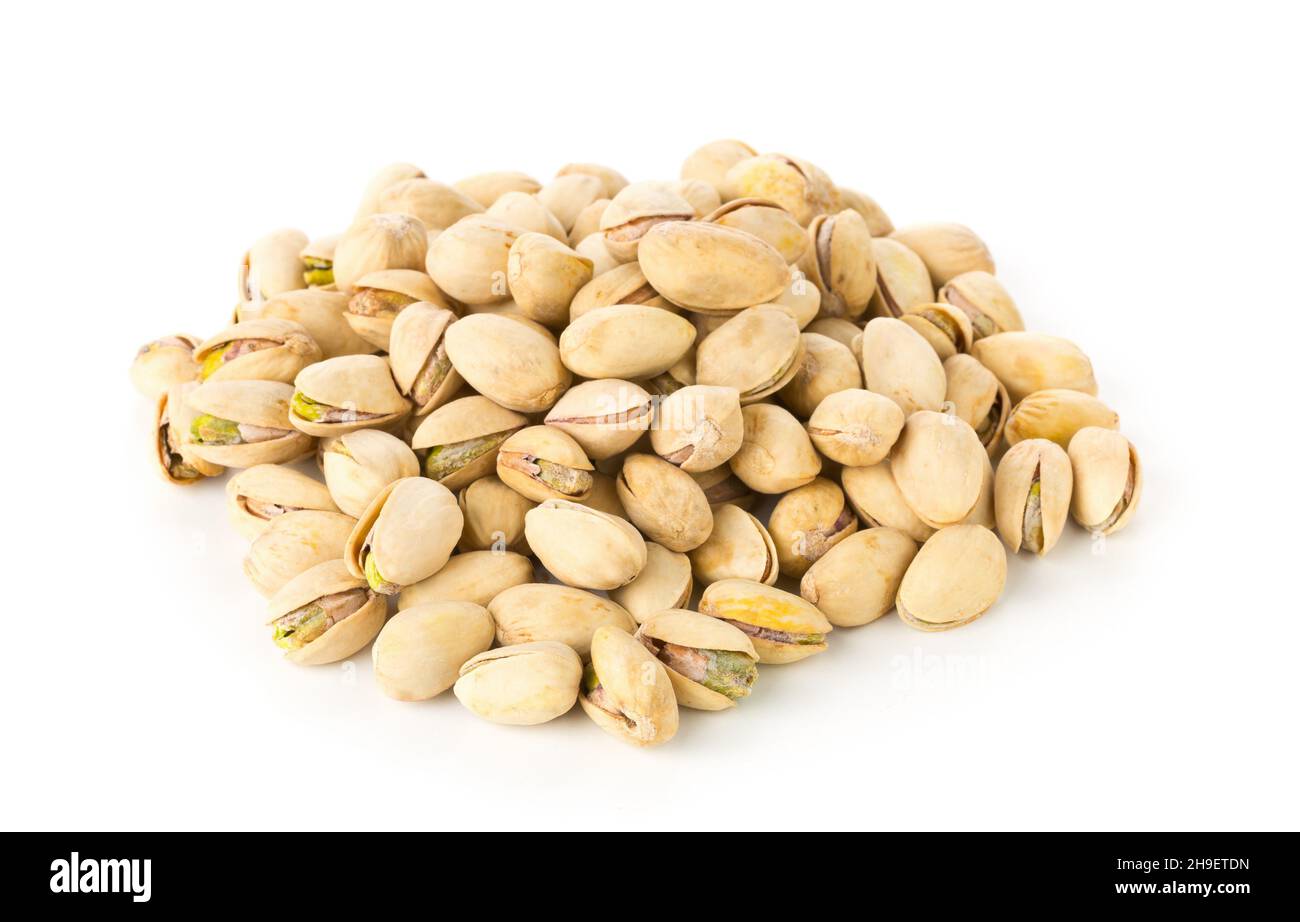 Heap of salted, roasted green pistachio nuts snack over white background, healthy food snack, selective focus Stock Photo