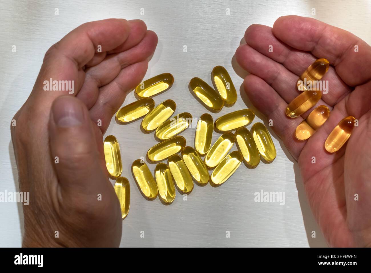 Vitamin capsules in hand palms close-up on white table Stock Photo
