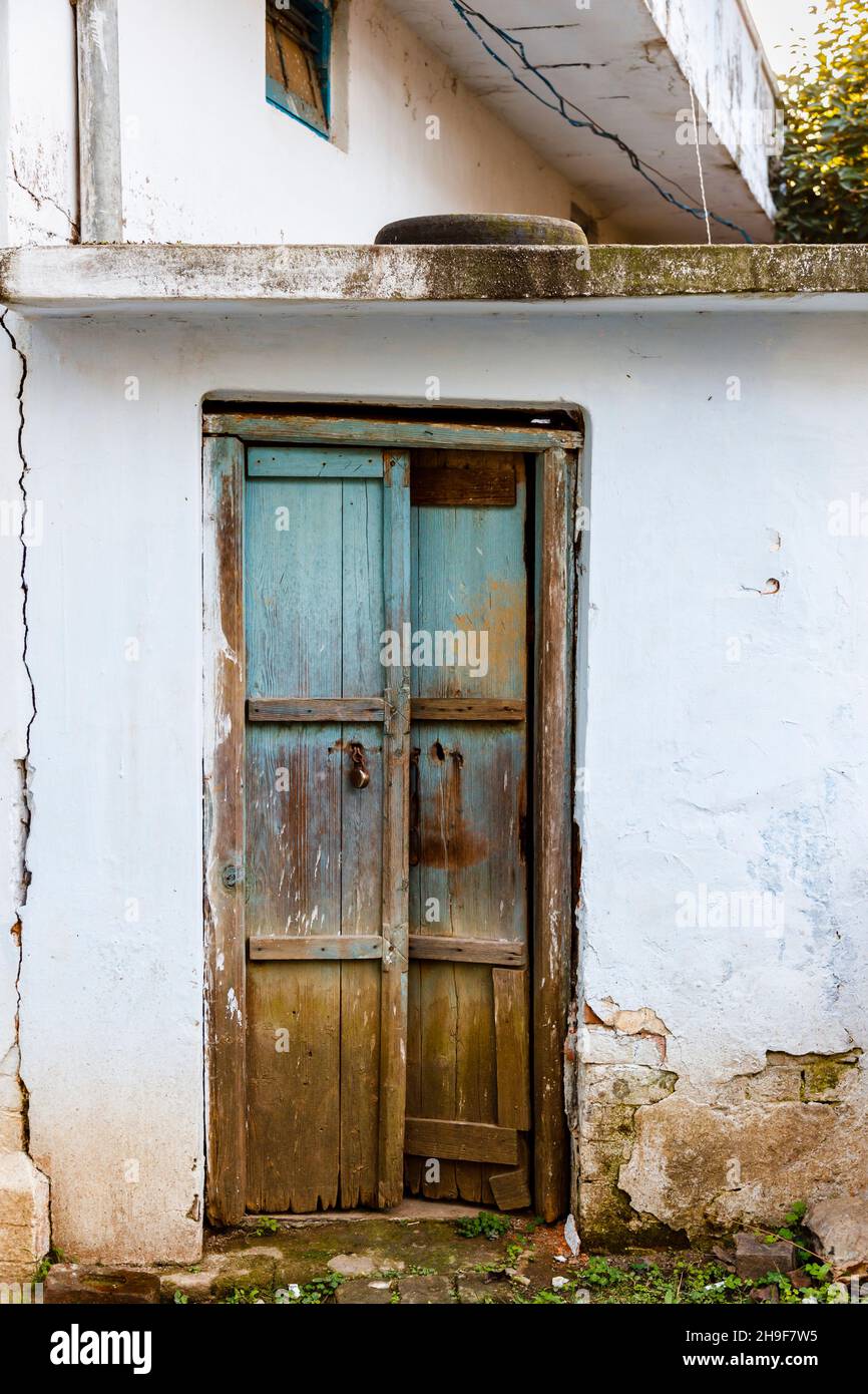 Dilapidated old wooden door in the white wall of a building in Pragpur, a heritage village in Kagra district, Himachal Pradesh, India Stock Photo