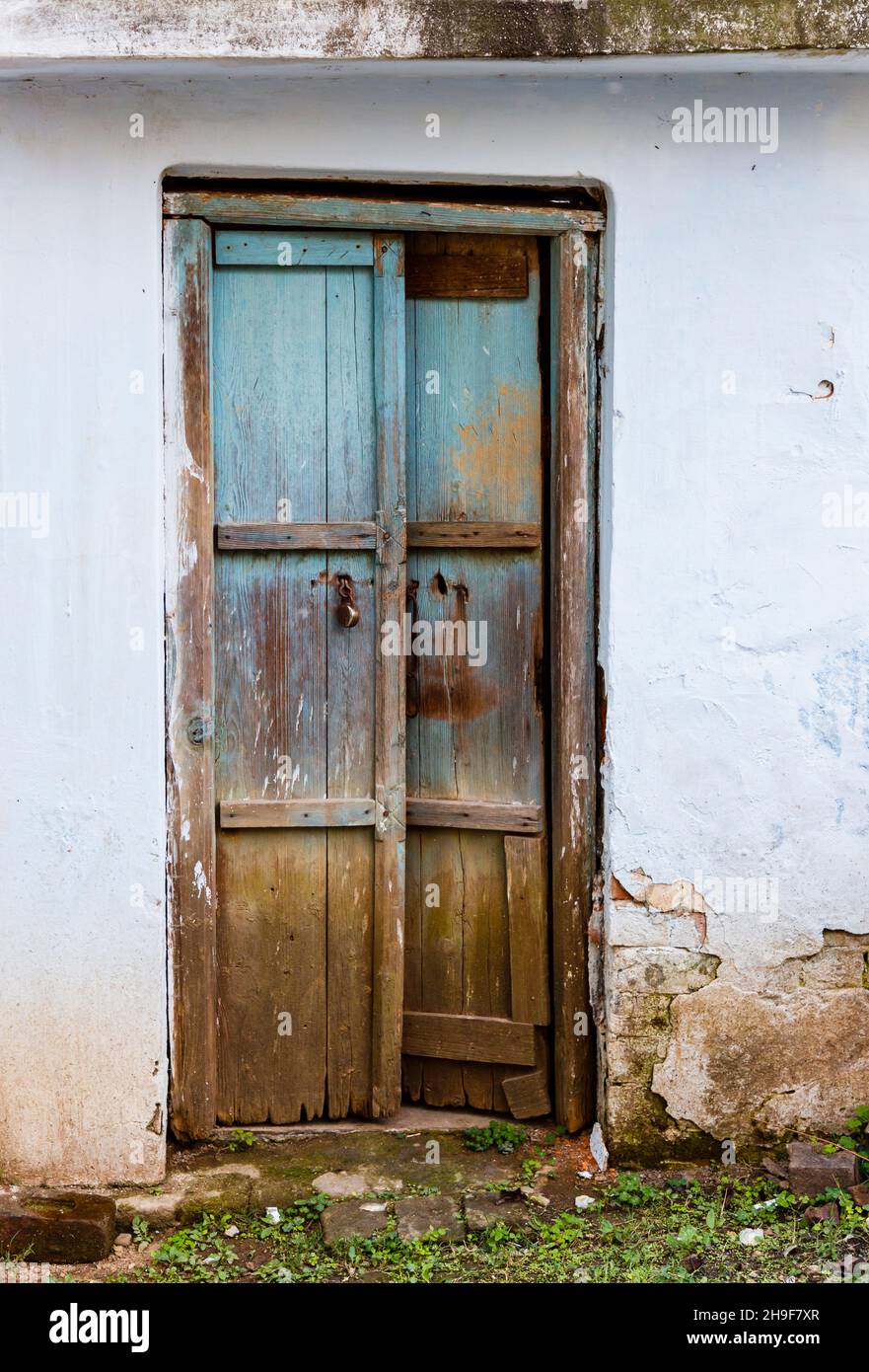 Dilapidated old wooden door in the white wall of a building in Pragpur, a heritage village in Kagra district, Himachal Pradesh, India Stock Photo