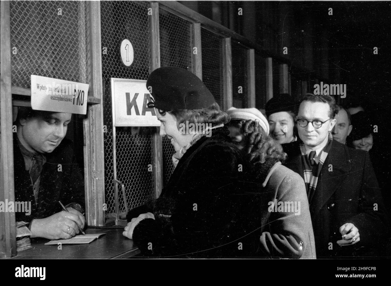 Warszawa, 1948-01-23. Pocztowa Kasa Oszczêdnoœci w Warszawie. Nz. interesanci przy okienku wp³at na ksi¹¿eczki oszczêdnoœciowe. bb/mgs  PAP      Warsaw, Jan. 23, 1948. The Post Saving Fund (PKO) in Warsaw. Pictured:customers paying money to their saving account.  bb/mgs  PAP Stock Photo