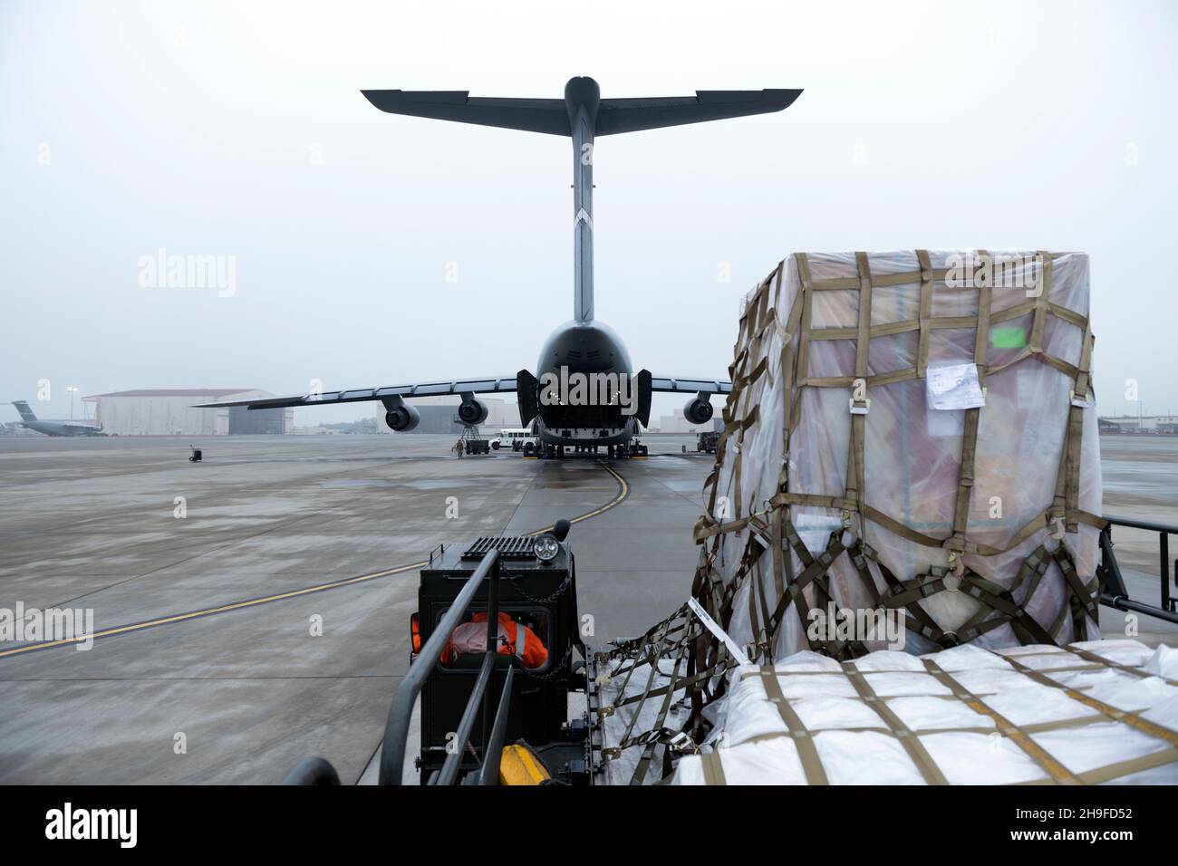 Cargo on a K-loader approaches a C-5M Super Galaxy Dec. 5, 2021, at Travis Air Force Base, California. In coordination with the Defense Logistics Agency, Travis AFB provided aircrew, airlift and aerial port support to move 1,300 cases of water weighing over 38,000 pounds and other supplies to joint service partners in Hawaii. (U.S. Air Force photo by Senior Airman Jonathon Carnell) Stock Photo