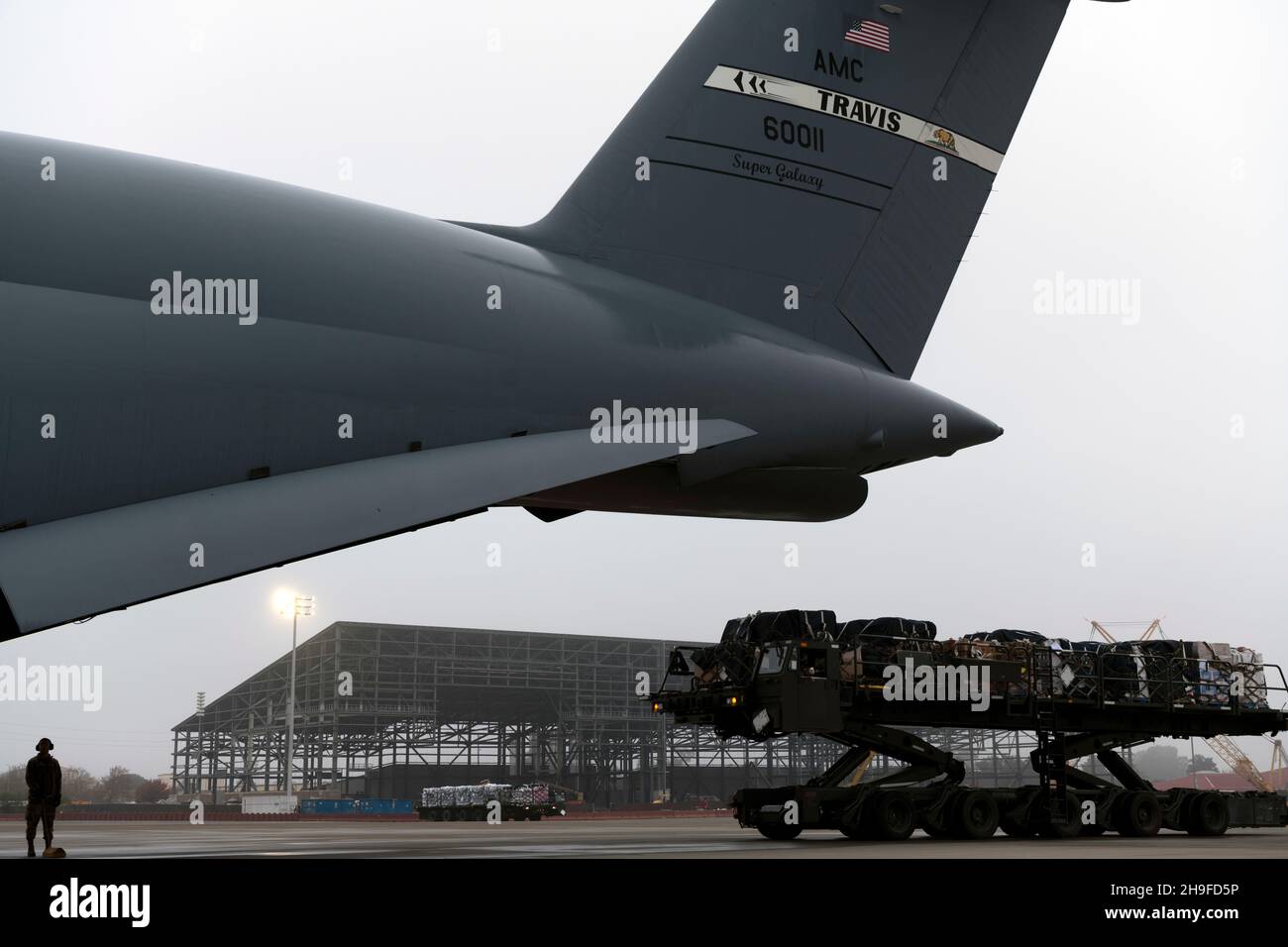 Cargo on a K-loader approaches a C-5M Super Galaxy Dec. 5, 2021, at Travis Air Force Base, California. In coordination with the Defense Logistics Agency, Travis AFB provided aircrew, airlift and aerial port support to move 1,300 cases of water weighing over 38,000 pounds and other supplies to joint service partners in Hawaii. (U.S. Air Force photo by Senior Airman Jonathon Carnell) Stock Photo