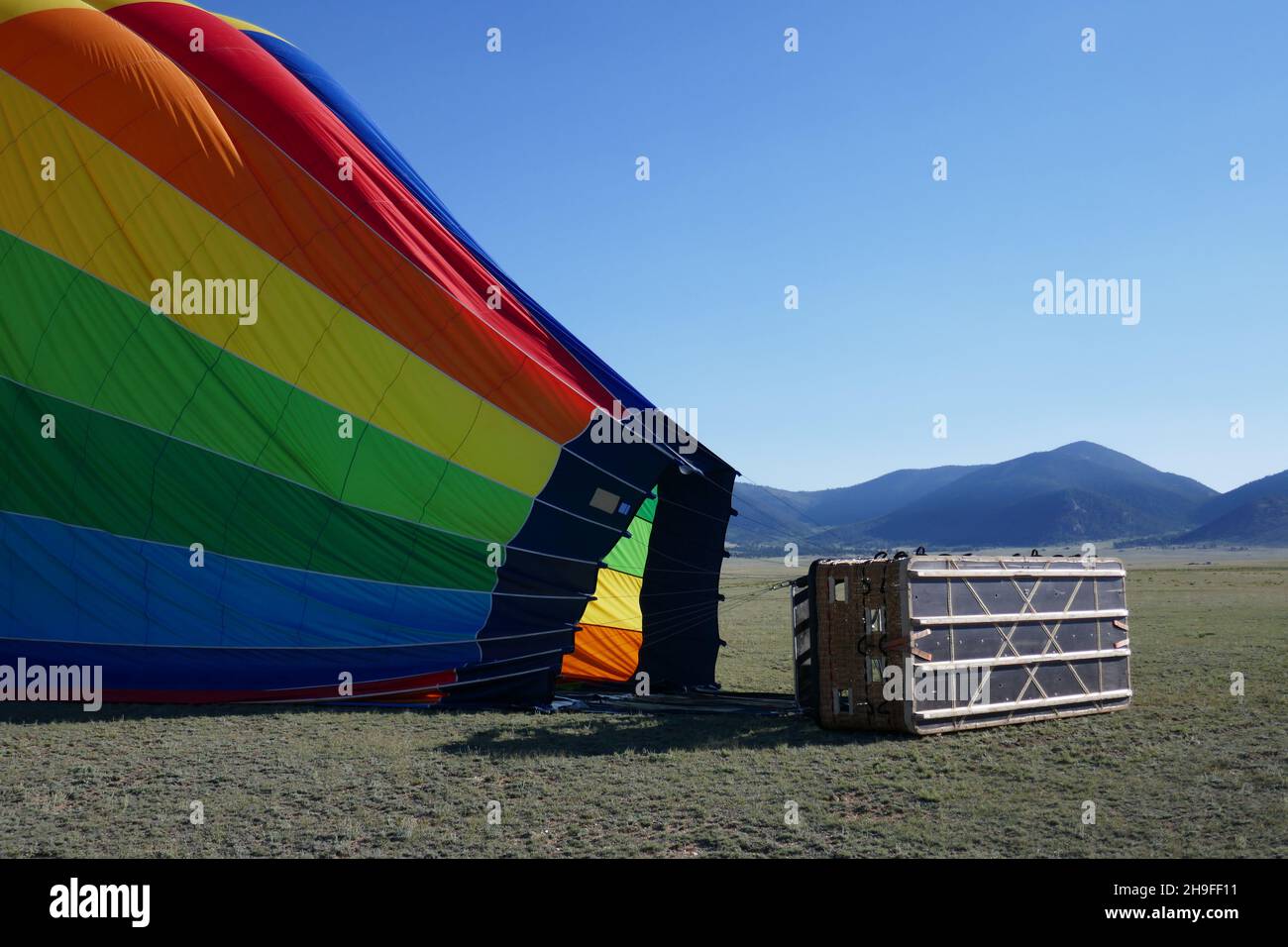 Side view of partially deflated hot air balloon with attached passenger basket Stock Photo