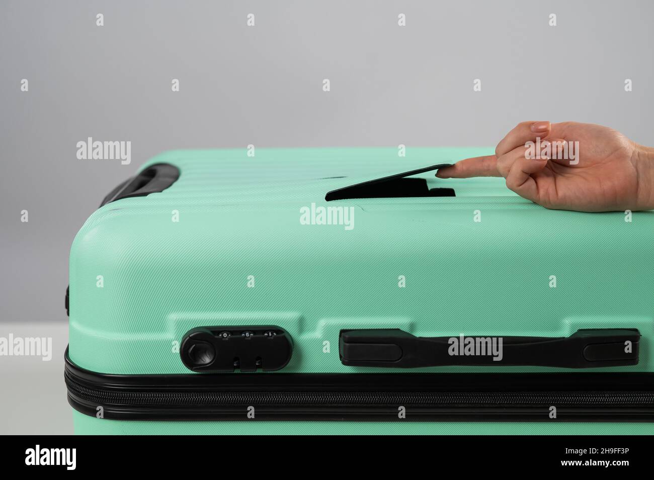 A woman demonstrates a broken suitcase on a white background. Damaged