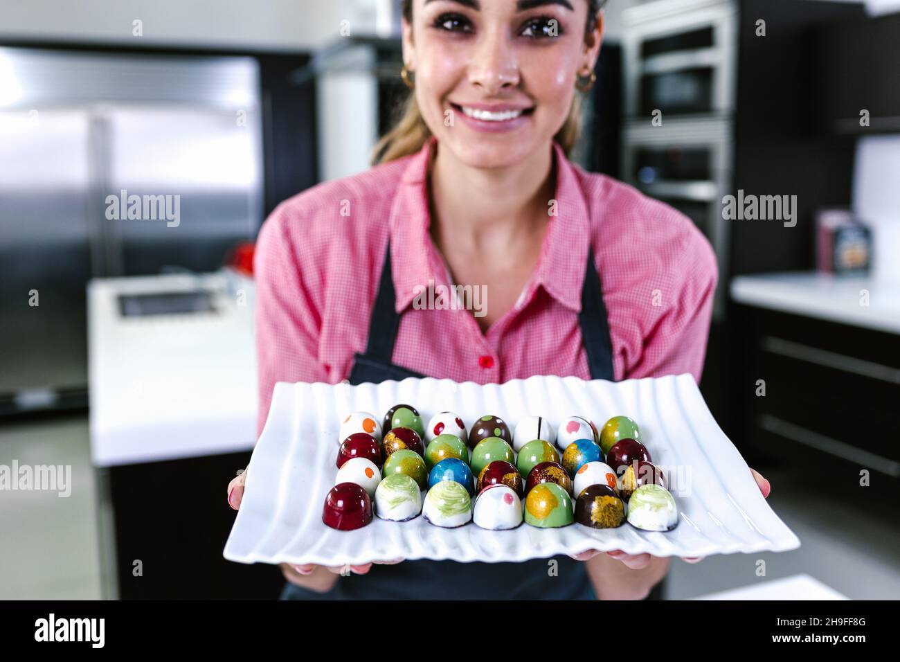 latin young woman pastry chef preparing delicious sweets chocolates at kitchen in Mexico Latin America Stock Photo