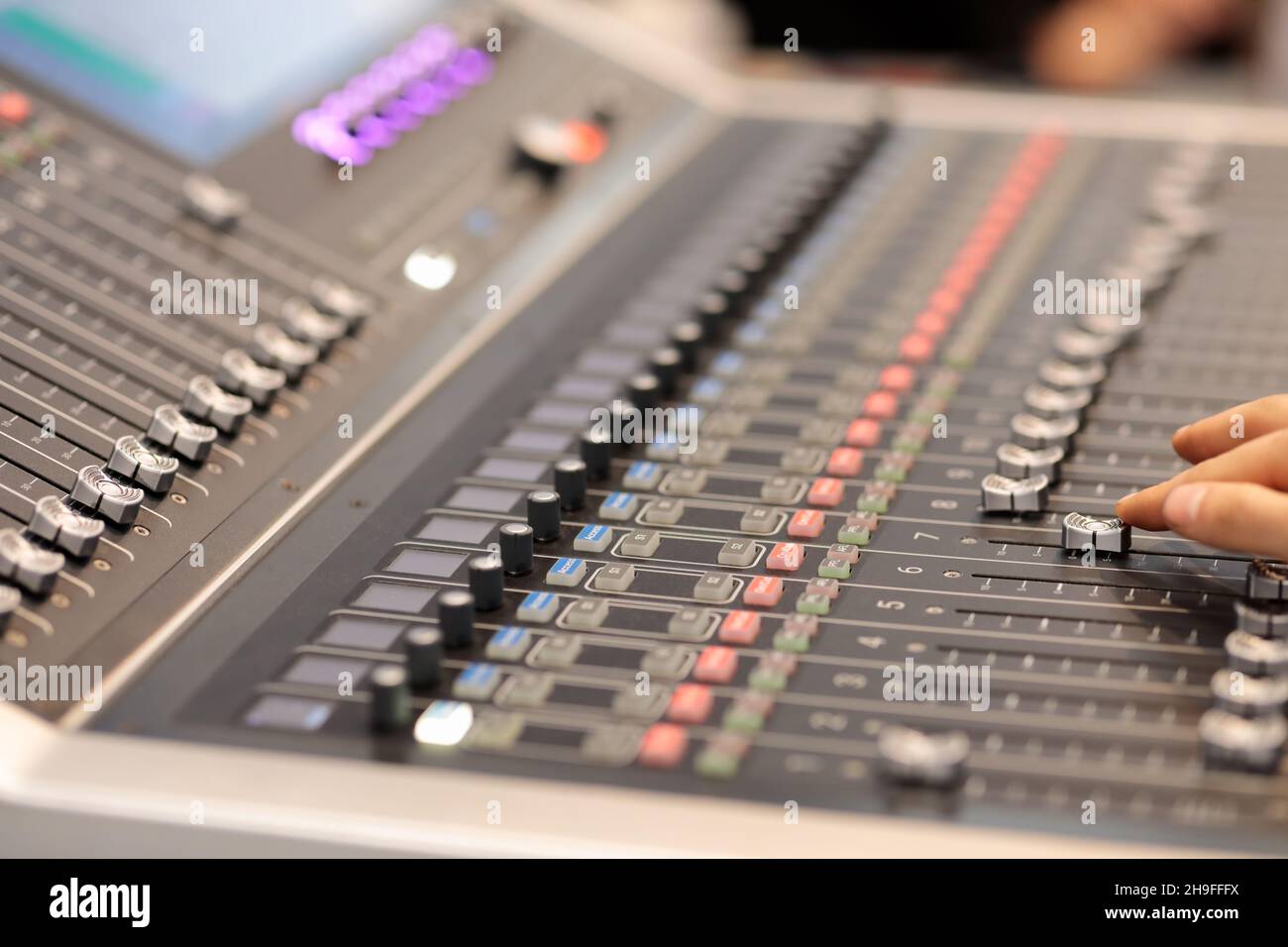 Hand of sound engineer adjusting faders on an audio mixing console. Selective focus. Stock Photo