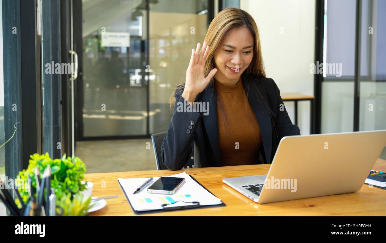 Attractive business woman video confronting via laptop computer with her business partner at the office. remote working concept. Stock Photo