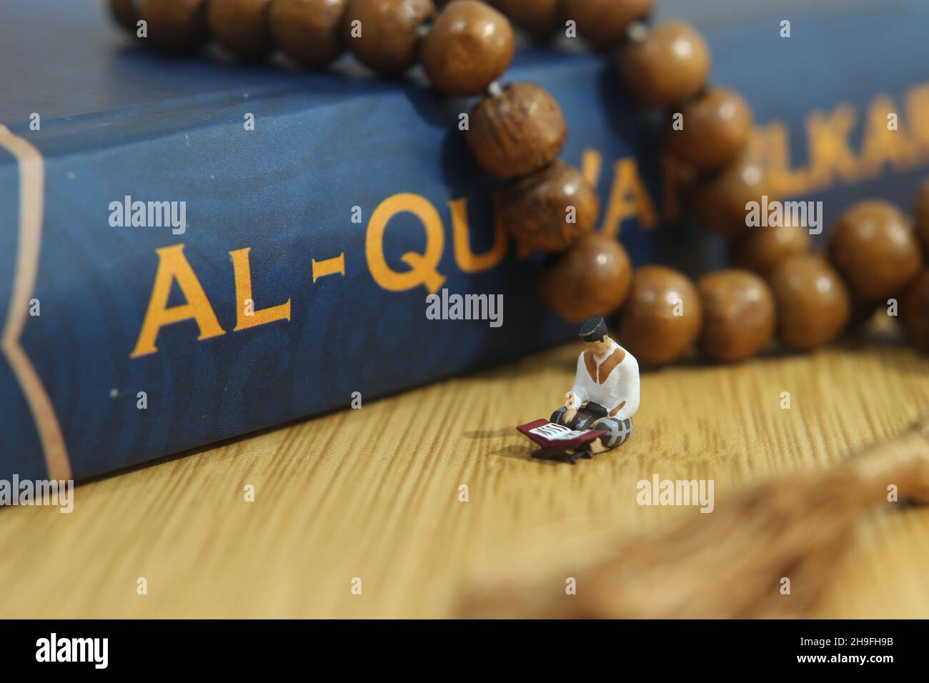 Simple Conceptual Photo, Islam Man or Muslim, Read Al Quran, Al Qur'an Near The Real One and Wooden Prayer Bead Stock Photo