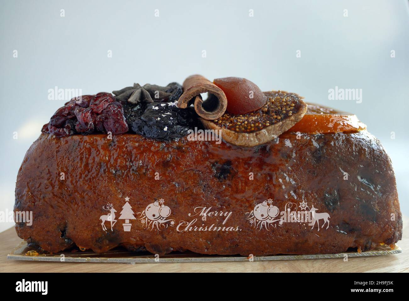 Close-up side view loaf of fruitcakes St-Germain elderflower liqueur seasons cake brown color with Merry Christmas Stock Photo