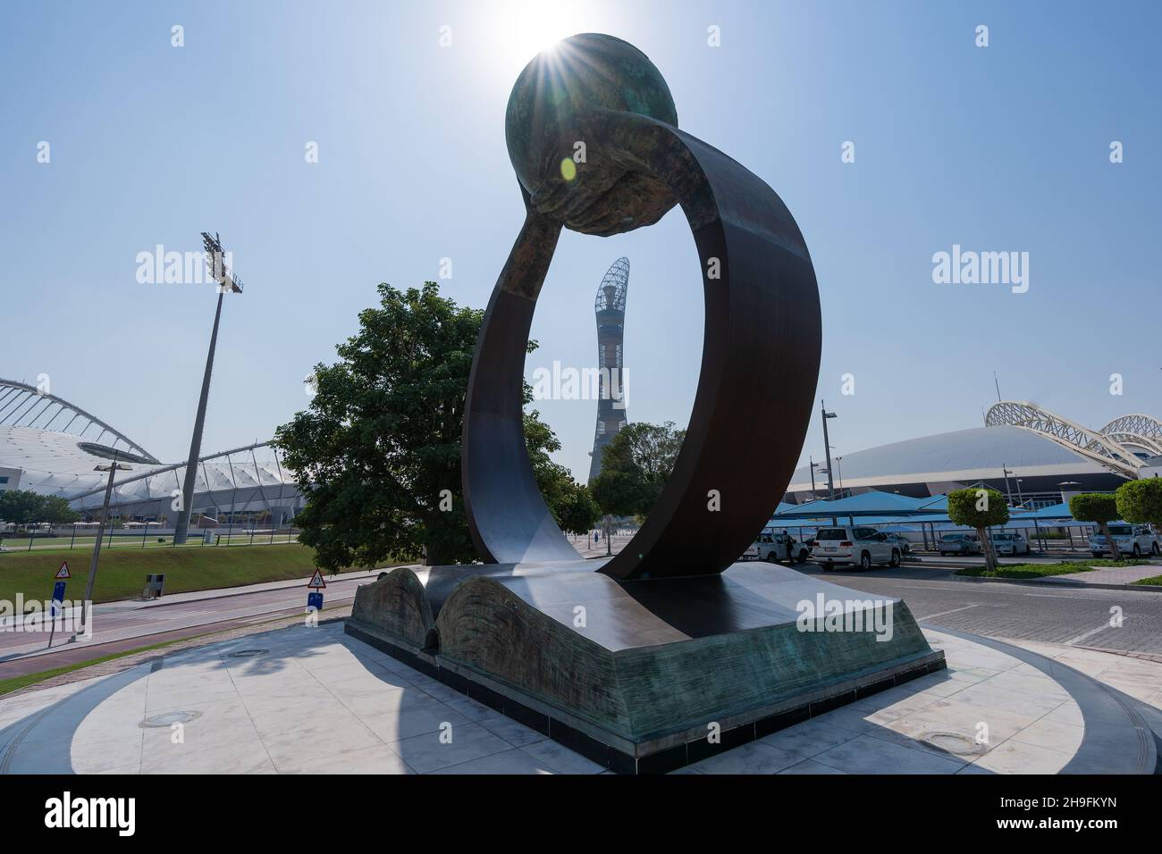 QATAR - NOV 13, 2021:A sculpture of hands rising from a book support the globe sculpture in Aspire Doha.The 2022 buildings is framed between the arms. Stock Photo