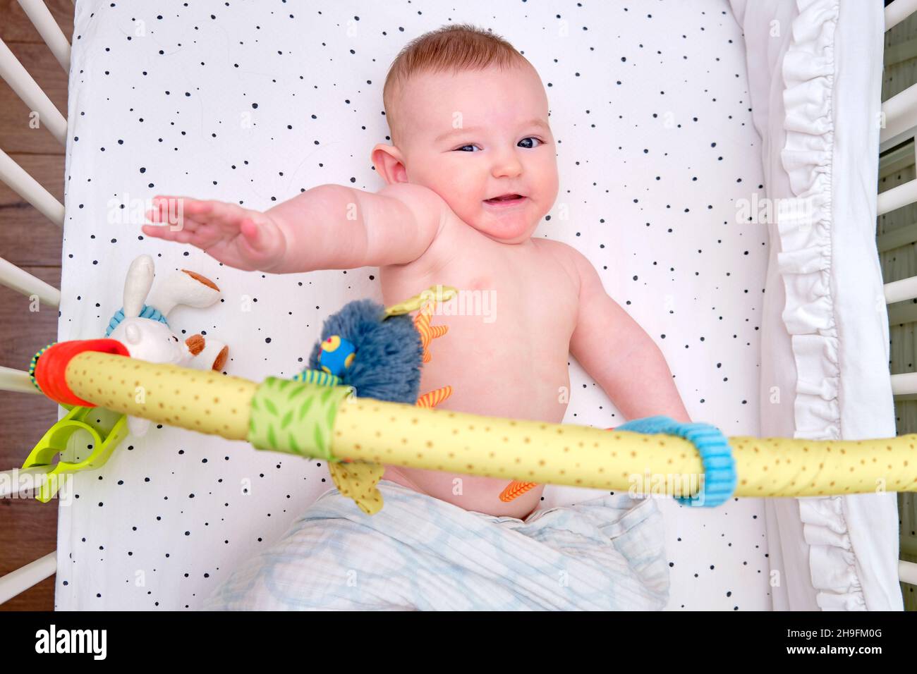 Infant baby refuses to play in bed with hanging toys, mobile above the
