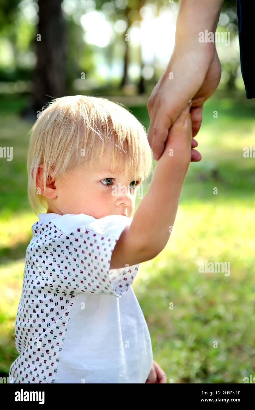 Sad Child hold the Parent Hand in the Summer Park Stock Photo