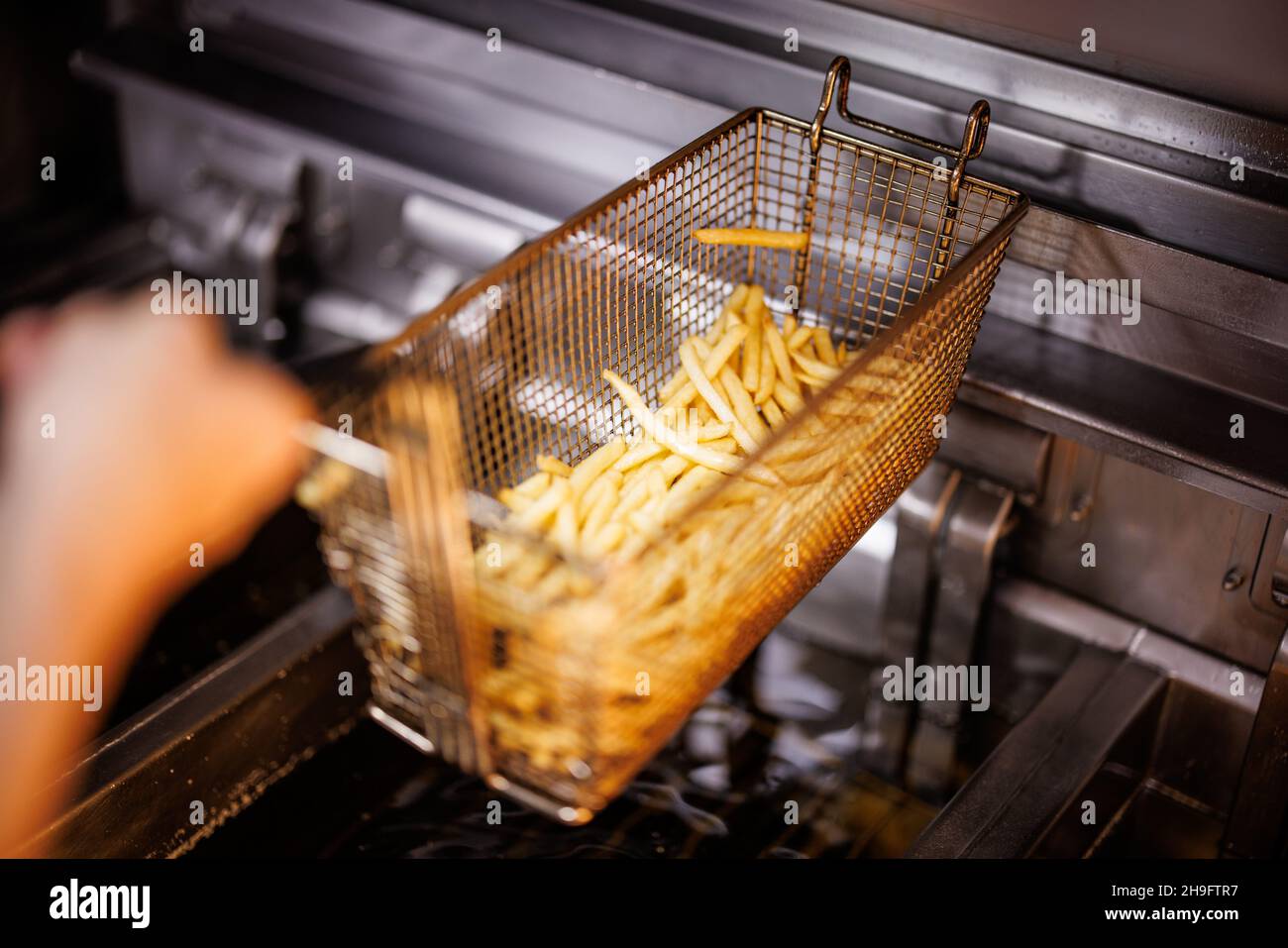 Munich, Germany. 02nd Dec, 2021. An employee takes a basket of French fries out of the fryer at a branch of the McDonald's fast food chain on Martin-Luther-Strasse in Giesing. The branch opened its doors on 4 December 1971 as the first McDonald's branch in Germany. Credit: Matthias Balk/dpa/Alamy Live News Stock Photo