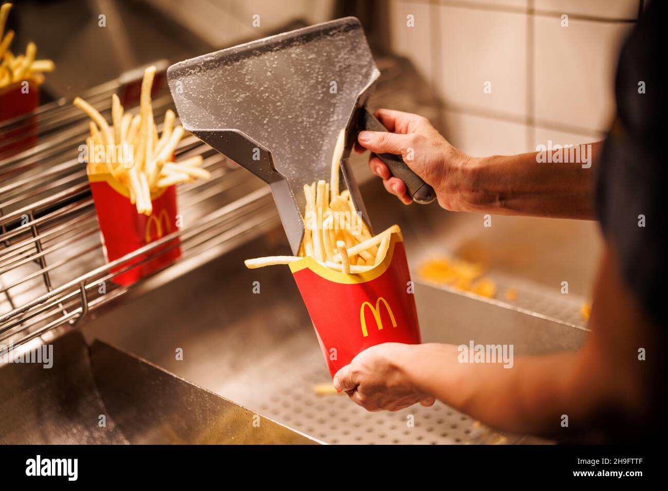 Munich, Germany. 02nd Dec, 2021. An employee fills a bag with French fries at a branch of the McDonald's fast food chain on Martin-Luther-Strasse in Giesing. The branch opened its doors on 4 December 1971 as the first McDonald's branch in Germany. Credit: Matthias Balk/dpa/Alamy Live News Stock Photo