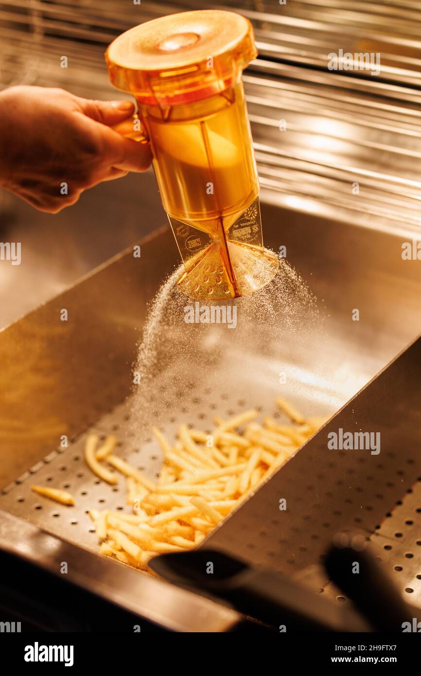 Munich, Germany. 02nd Dec, 2021. An employee salts French fries at a branch of the McDonald's fast food chain on Martin-Luther-Strasse in Giesing. The branch opened its doors on 4 December 1971 as the first McDonald's branch in Germany. Credit: Matthias Balk/dpa/Alamy Live News Stock Photo