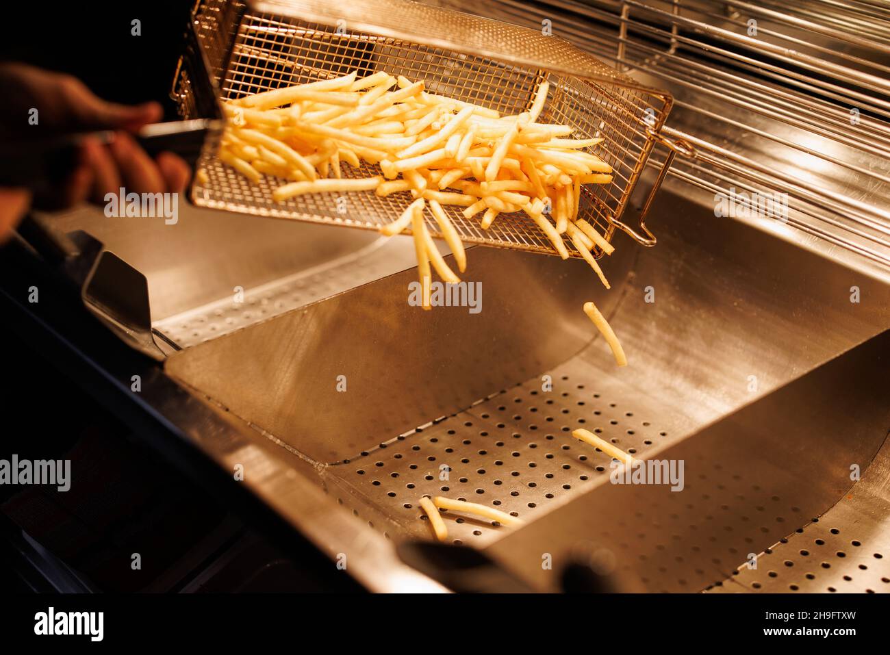 Munich, Germany. 02nd Dec, 2021. An employee pours French fries from a grill at a branch of the McDonald's fast food chain on Martin-Luther-Strasse in Giesing. The branch opened its doors on 4 December 1971 as the first McDonald's branch in Germany. Credit: Matthias Balk/dpa/Alamy Live News Stock Photo
