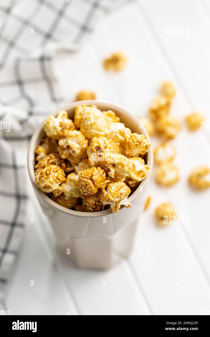 Sweet caramel popcorn in cup on white table. Stock Photo