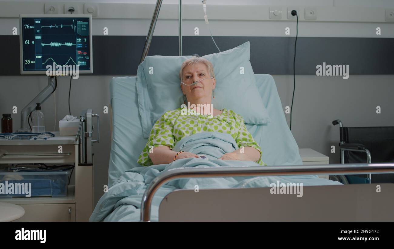 Portrait of senior patient laying in hospital ward bed with nasal
