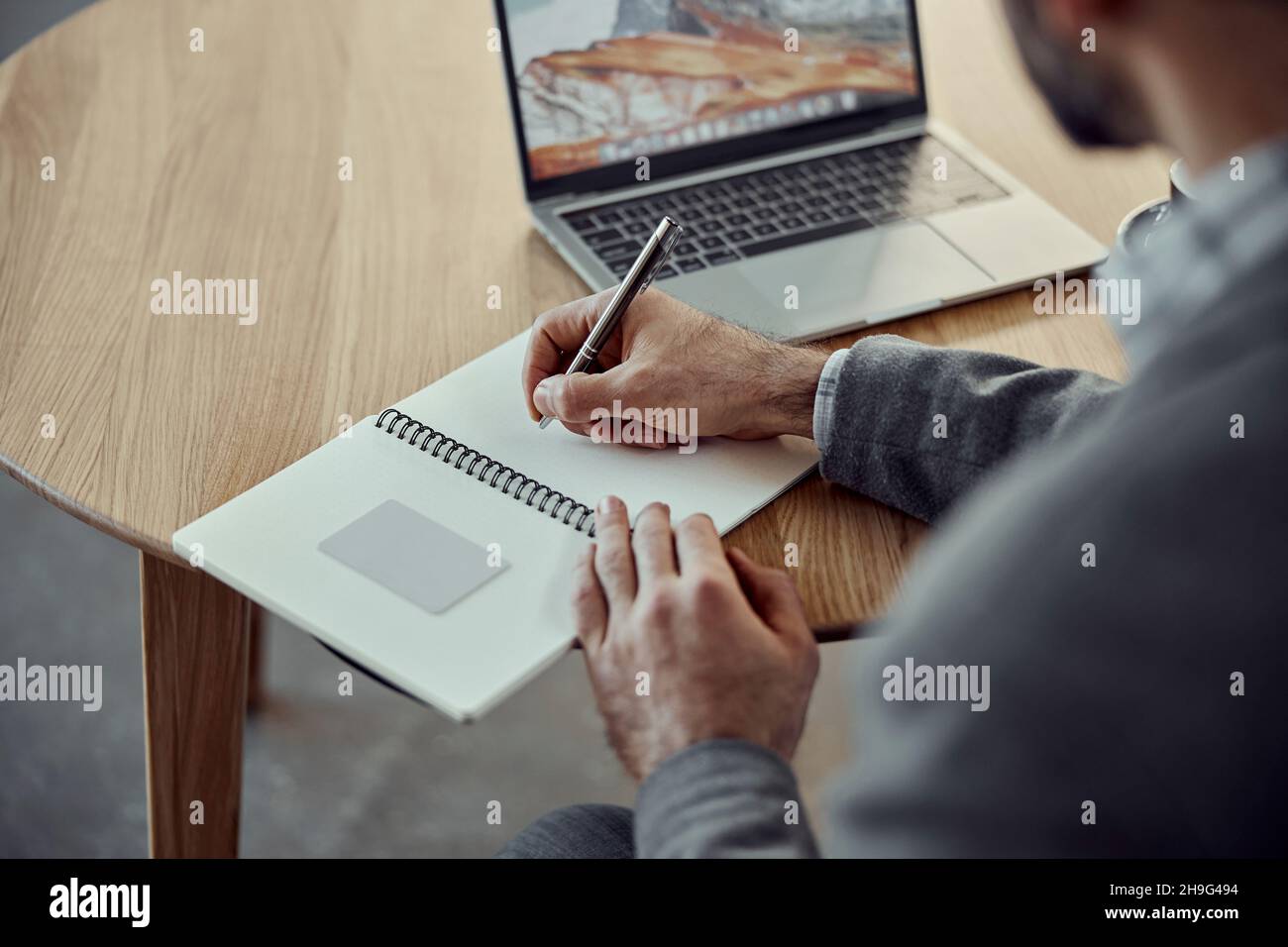 Young man using laptop and writing in notebook Stock Photo
